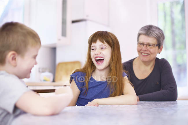Nonna e nipoti ridono al tavolo della cucina — Foto stock