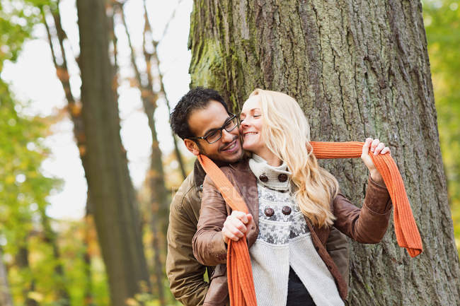 Couple souriant étreignant dans la forêt — Photo de stock