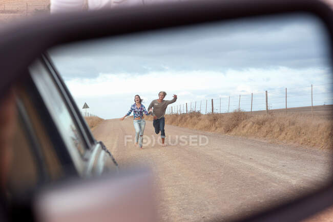 Paar läuft hinter Auto — Stockfoto