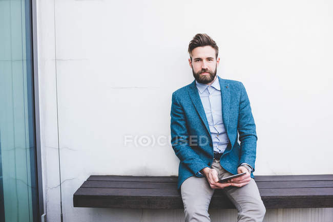 Retrato del joven hombre de negocios sentado en la terraza de la azotea de la oficina - foto de stock
