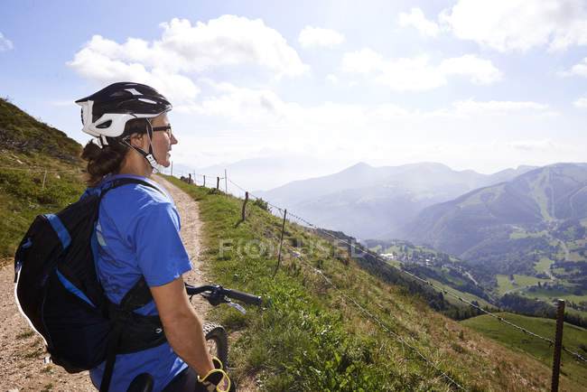 Ciclista vestindo capacete de ciclismo olhando para a vista das montanhas — Fotografia de Stock