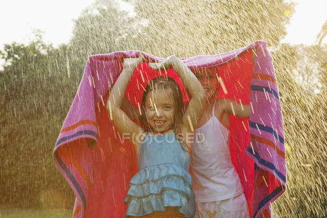 Mädchen stehen im Regen unter Handtuch — Stockfoto