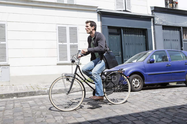 Mid adult man speeding down cobbled city street on bicycle — Stock Photo