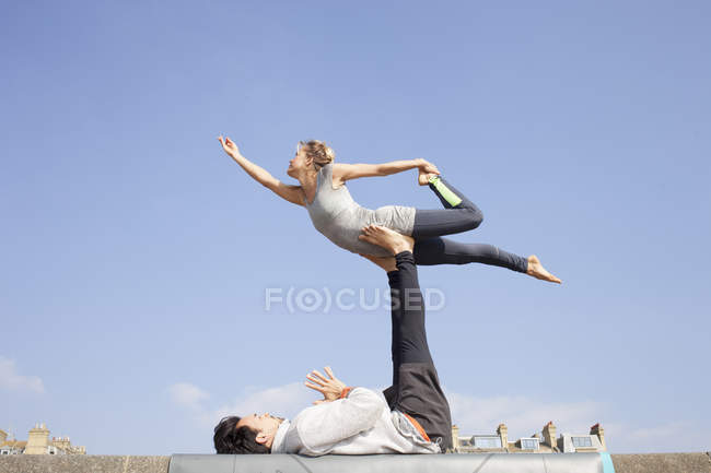 Hombre y mujer practicando yoga acrobático en la pared - foto de stock