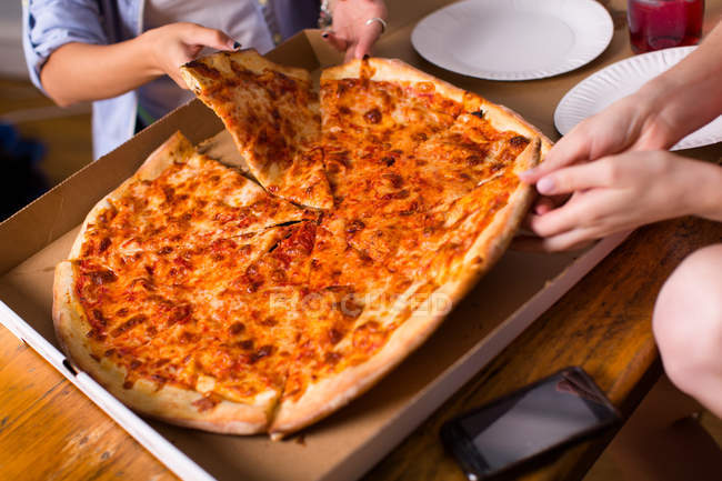 People sharing takeaway pizza, cropped shot — Stock Photo