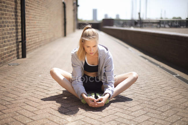 Runner stretching on walkway, Wapping, London — Stock Photo