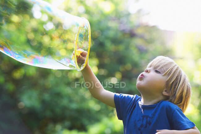 Ragazzo soffiando oversize bolla in cortile — Foto stock