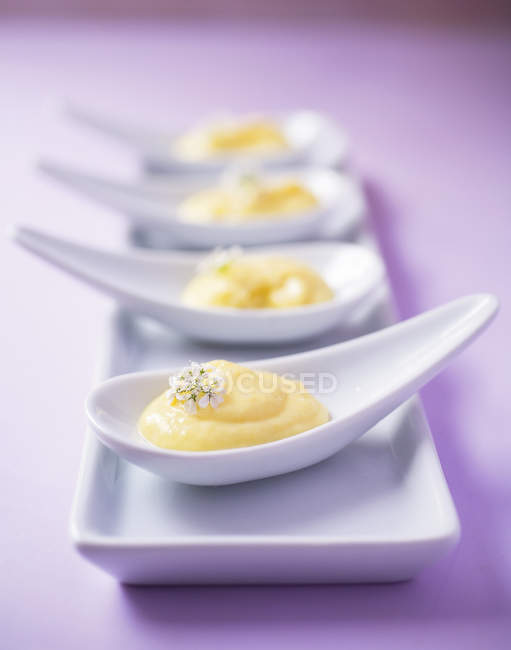 Four custard desserts on china spoons — Stock Photo