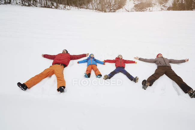 Parents and sons lying in snow covered landscape, Elmau, Bavaria, Germany — Stock Photo