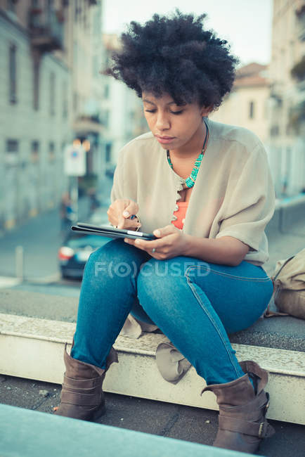 Young woman using touchscreen on digital tablet on edge of rooftop — Stock Photo