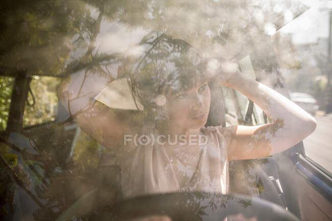 Молодая женщина чинит волосы в машине — стоковое фото