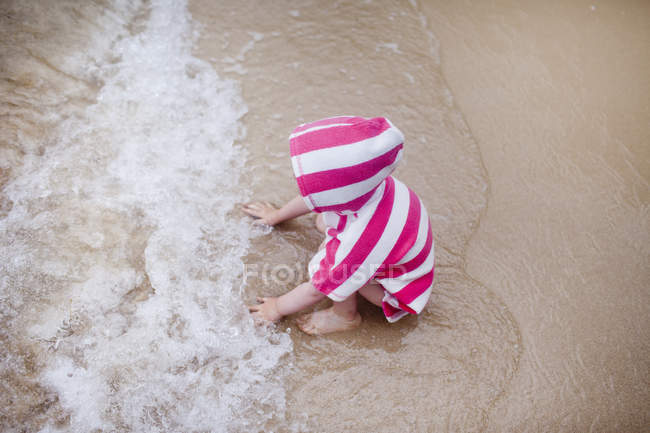 Baby girl sitting in the sea, rear view — Stock Photo