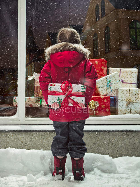 Girl holding Christmas present in snow — Stock Photo