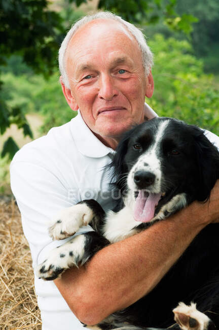 Senior man holding dog, portrait — Stock Photo