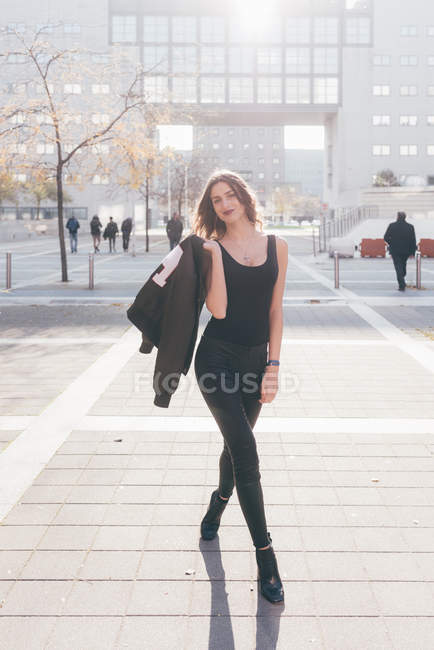 Retrato de mulher jovem ao ar livre, segurando jaqueta sobre ombro — Fotografia de Stock