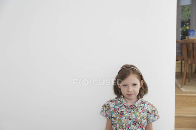 Portrait of shy young girl next to white wall — Stock Photo