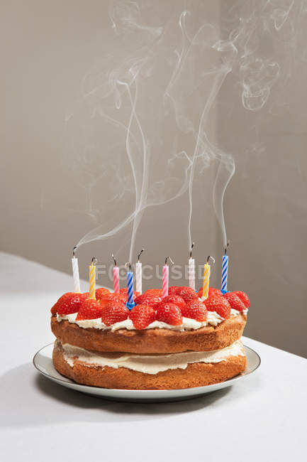 Velas humeantes en pastel de cumpleaños de fresa - foto de stock