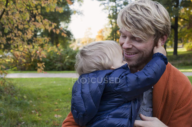 Батько і син обіймаються в парку — стокове фото