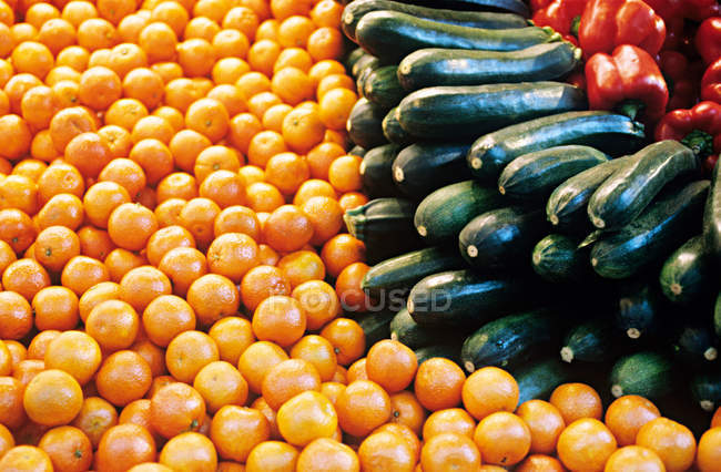Ripe bell peppers, courgettes and oranges at market — Stock Photo