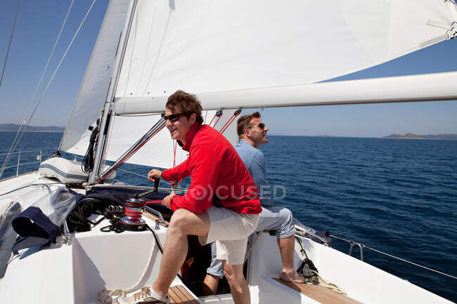 Two men setting sail on yacht — Stock Photo