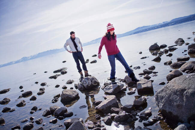 Couple marchant sur des rochers près d'un lac — Photo de stock