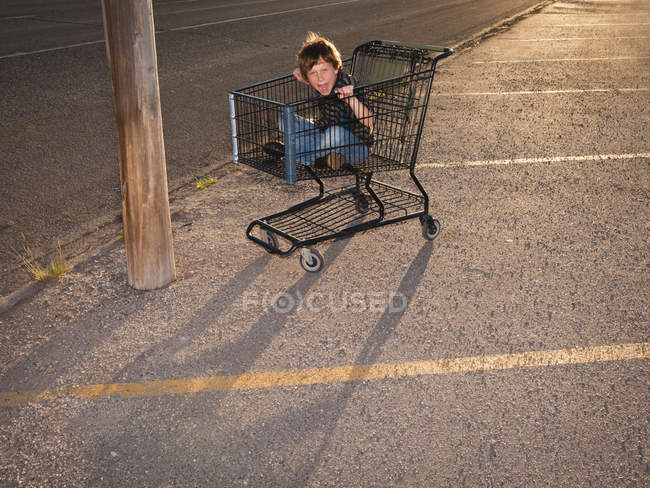 Menino usando carrinho de compras como veículo — Fotografia de Stock