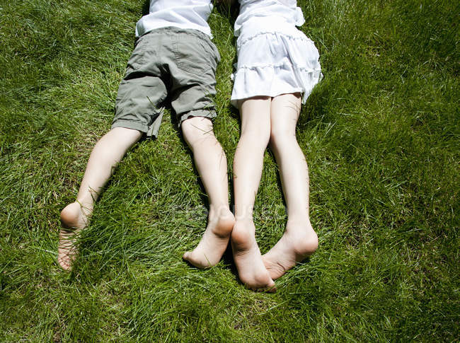 Вид зверху на ноги брата і сестер, коли вони лежать на траві — стокове фото