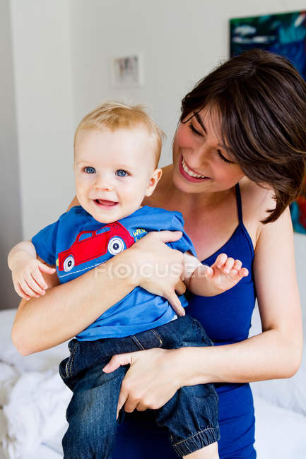 Mother holding baby in bedroom — Stock Photo