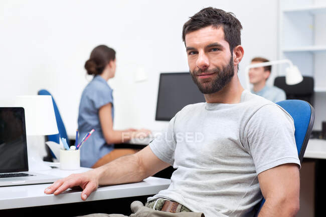 Homme adulte moyen assis au bureau — Photo de stock