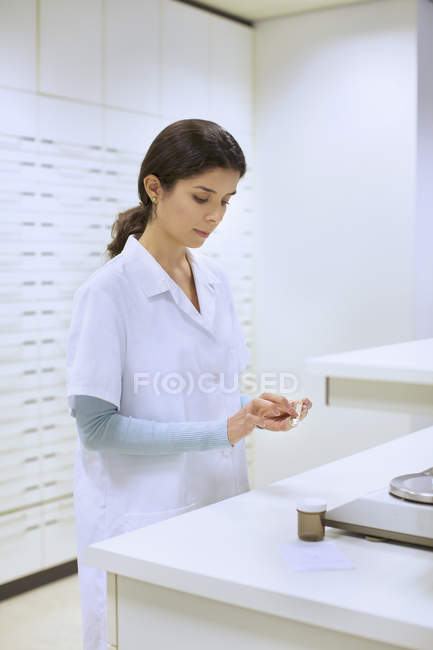 Young female pharmacist weighing medicines in pharmacy — Stock Photo