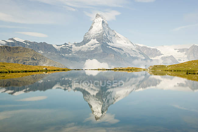 Засніжена скеляста гора, що відображає в озері воду — стокове фото