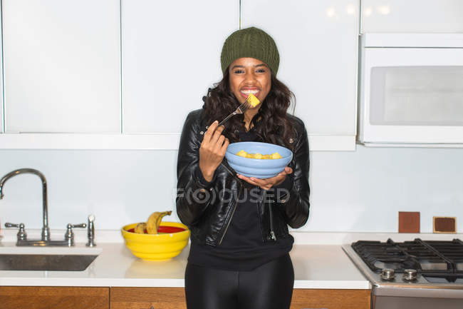 Woman eating fruit in kitchen — Stock Photo