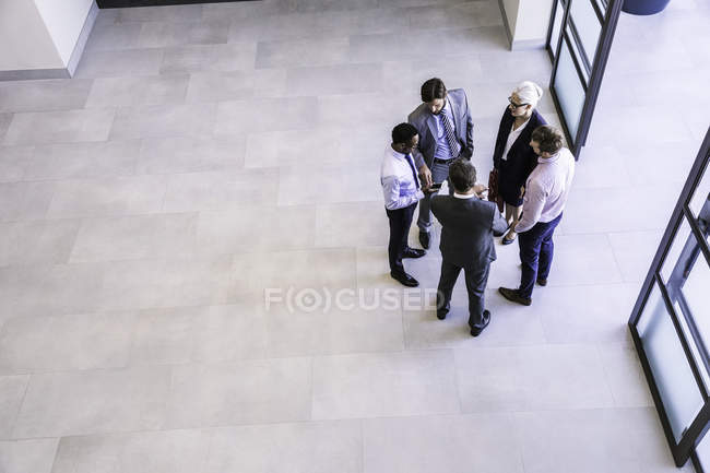 Высокий угол обзора бизнесвумен и мужчины обсуждают в офисном атриуме — стоковое фото