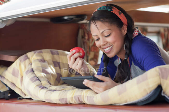 Молода жінка, використовуючи цифровий планшет у фургоні, посміхається — стокове фото