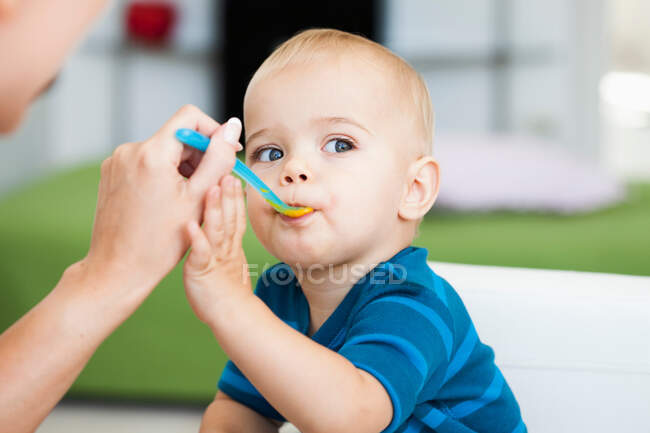 Baby sitting in chair being fed — Stock Photo