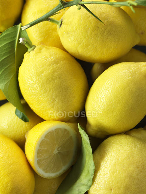 Pila de limones frescos con hojas, tiro de cerca - foto de stock