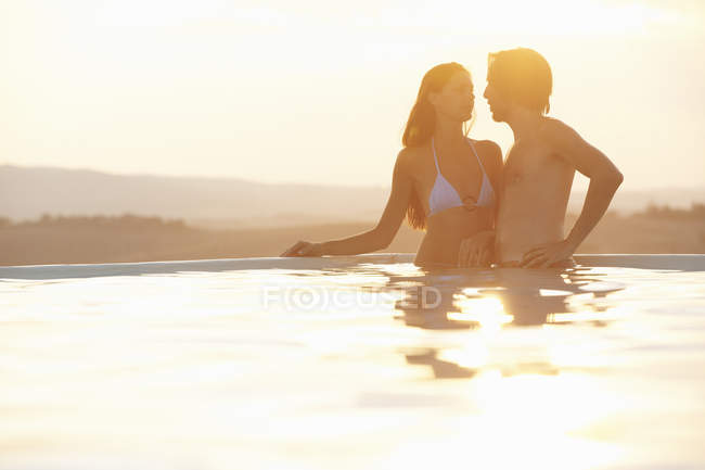 Romantic couple holding hands in outdoor swimming pool — Stock Photo