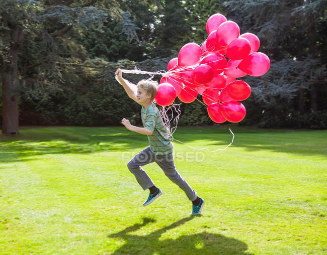 Мальчик с кучей воздушных шаров на улице — стоковое фото
