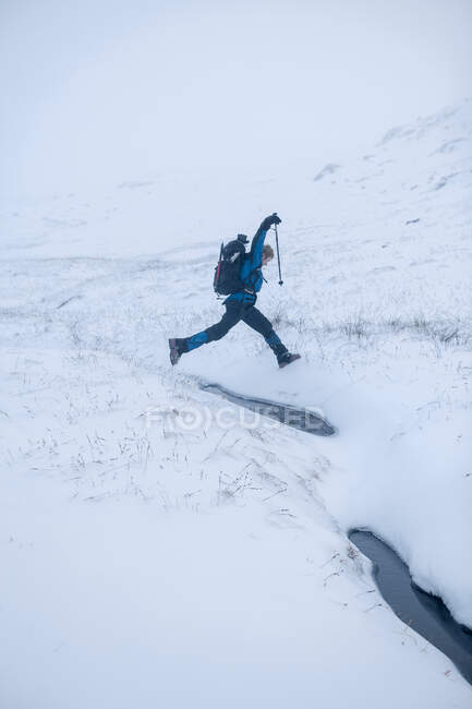 Hiker jumping in snowy landscape — Stock Photo