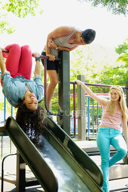 Three adult friends playing on a slide — Stock Photo