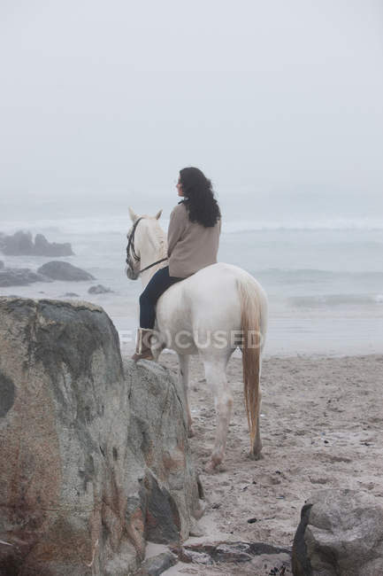Mujer montar a caballo en la playa - foto de stock