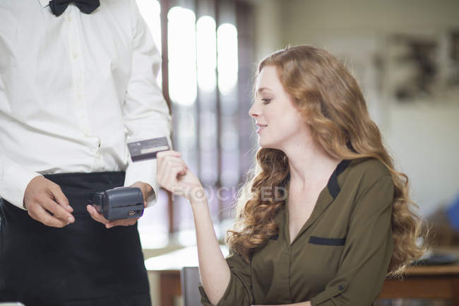 Молода жінка оплачує рахунок кредитною карткою в ресторані — стокове фото