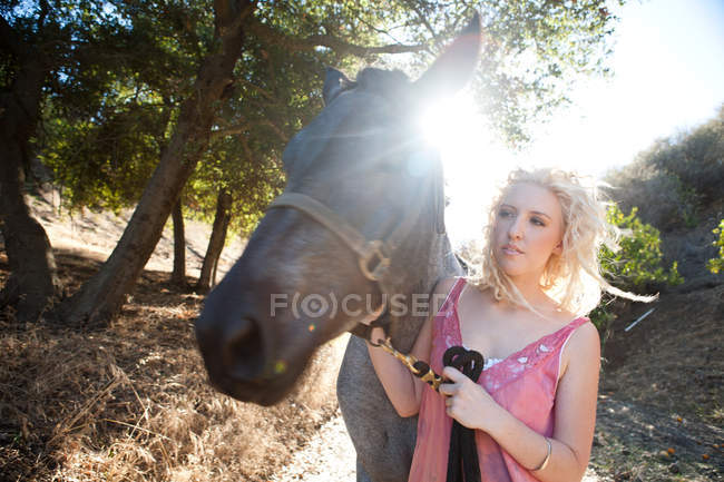 Young woman with horse in sunlight — Stock Photo