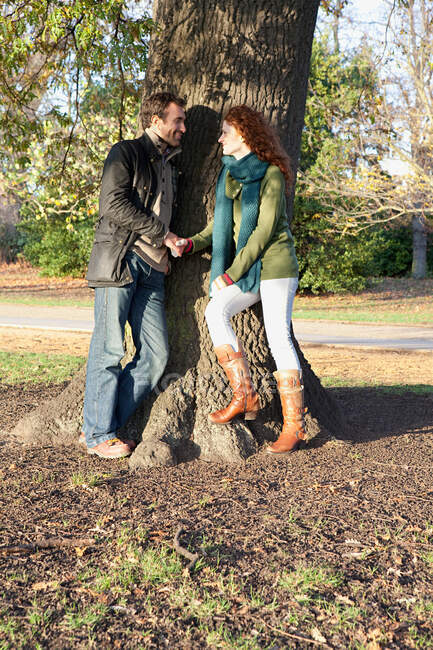 Um casal de pé cara a cara ao lado de uma árvore — Fotografia de Stock