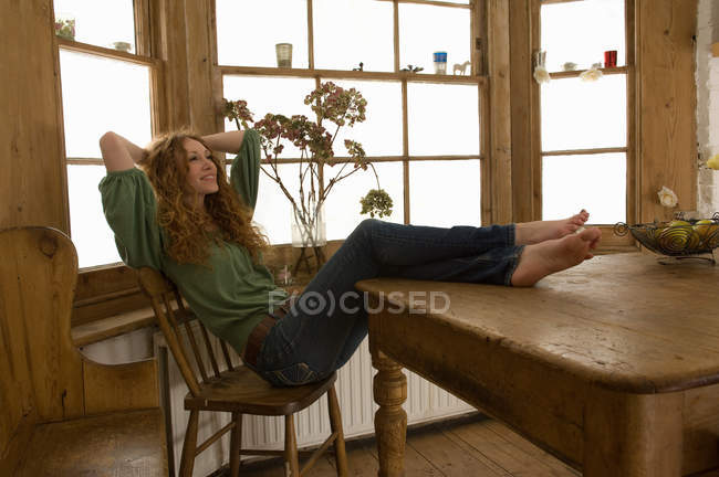 Жінка розслабляється за кухонним столом — стокове фото