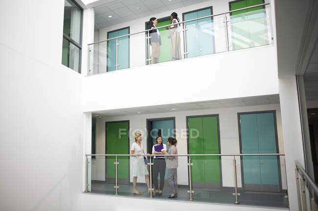 Colegas femeninas en balcón en edificio de oficinas - foto de stock