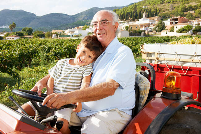 Grand-père et garçon assis sur tracteur — Photo de stock
