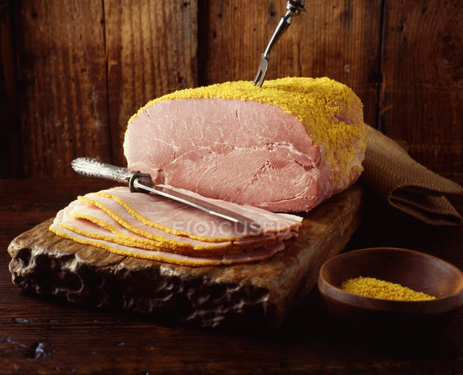 Whole breaded ham on wooden chopping board — Stock Photo