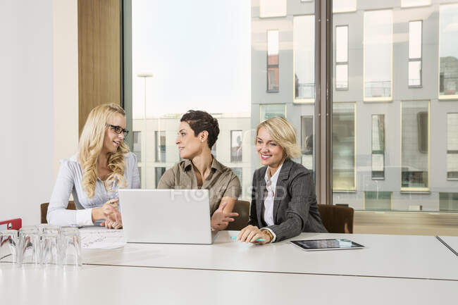 Businesswomen sitting at conference table using laptop — Stock Photo
