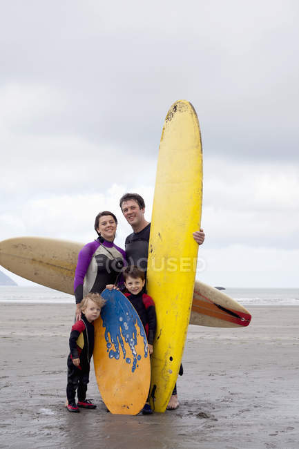 Portrait of family with two boys with surfboards on beach — Stock Photo